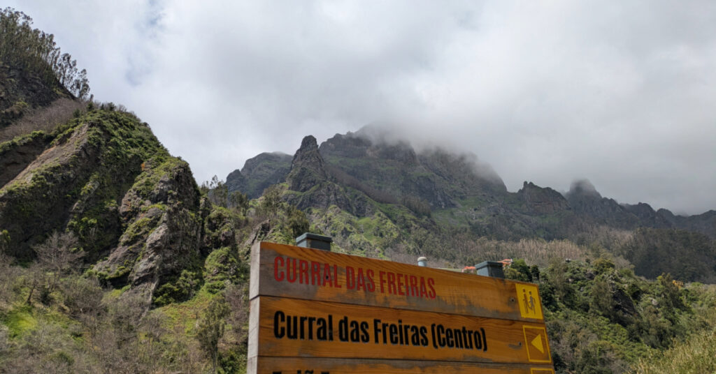 Signs to Curral das Freiras, with clouds covering the mountains in the background.