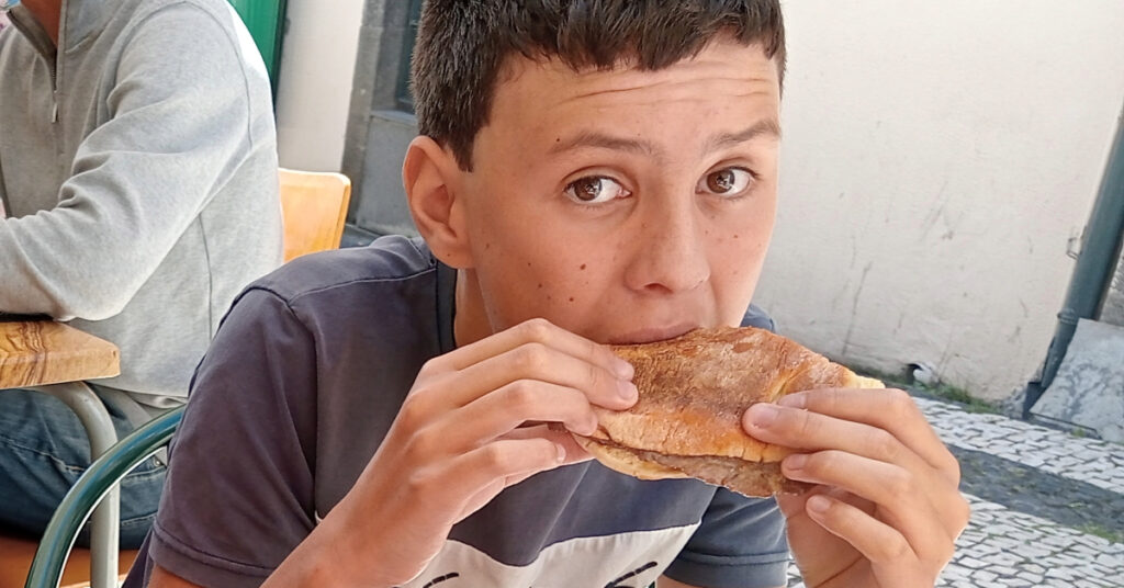 Alfie digs in to a delicious prego no bolo do caco.