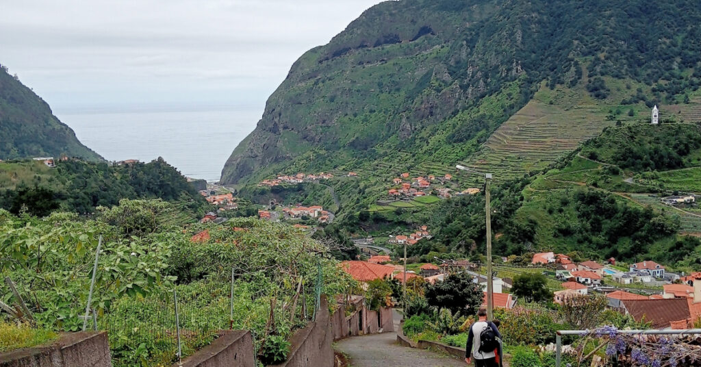 John and Alfie walk back down towards São Vicente, past houses, and thriving gardens and allotments. The Nossa Senhora de Fátima Chapel is visible, alone on a hill, in the background.