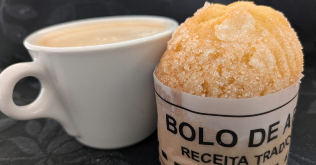 A cup of coffee and a sugar-crusted bolo de arroz.