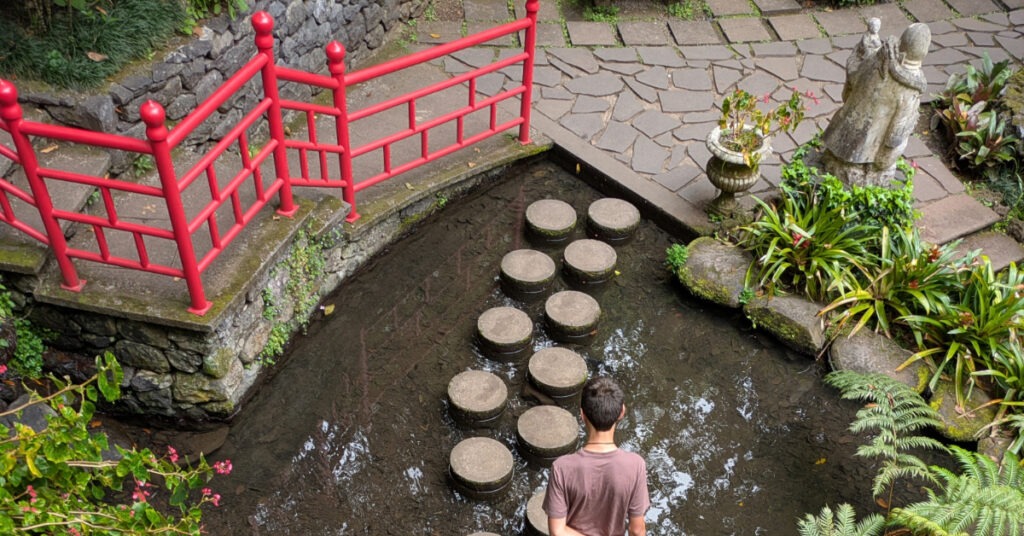 Alfie walks across some perfectly round stepping stones in a pond in the oriental section of Monte Palace Gardens.